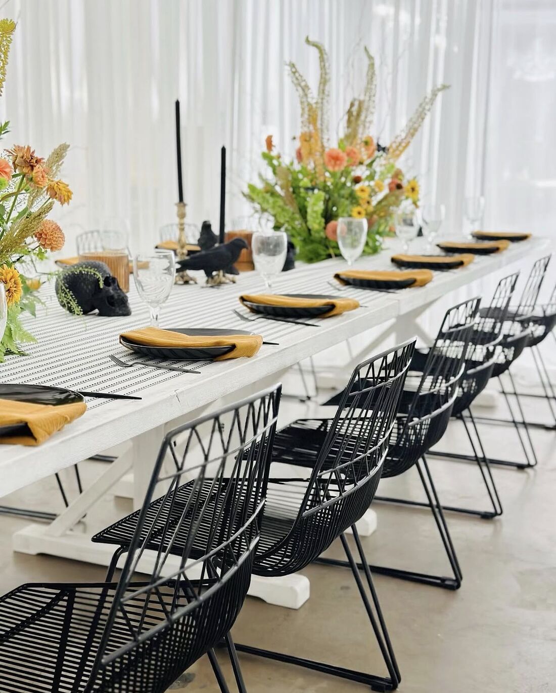 Black wire chairs, black taper candles and marigold napkins at a moody editorial dinner