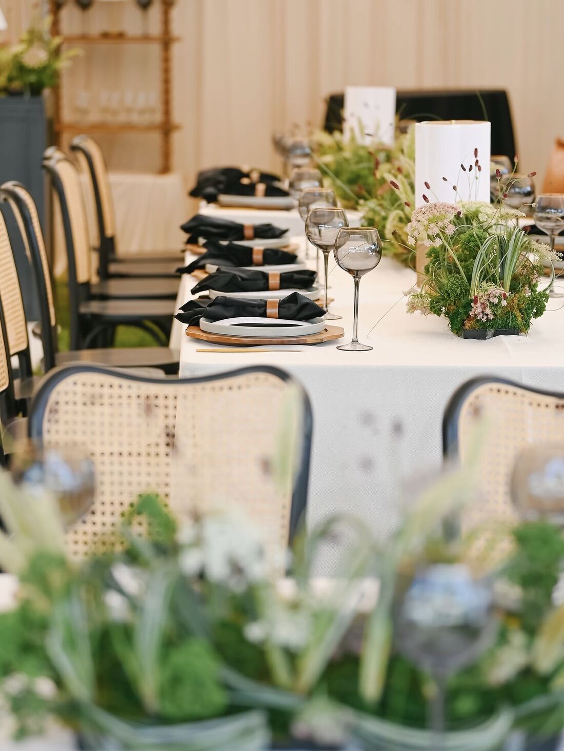 Black cane bentwood chairs around a styled table with black napkins and smoked glassware