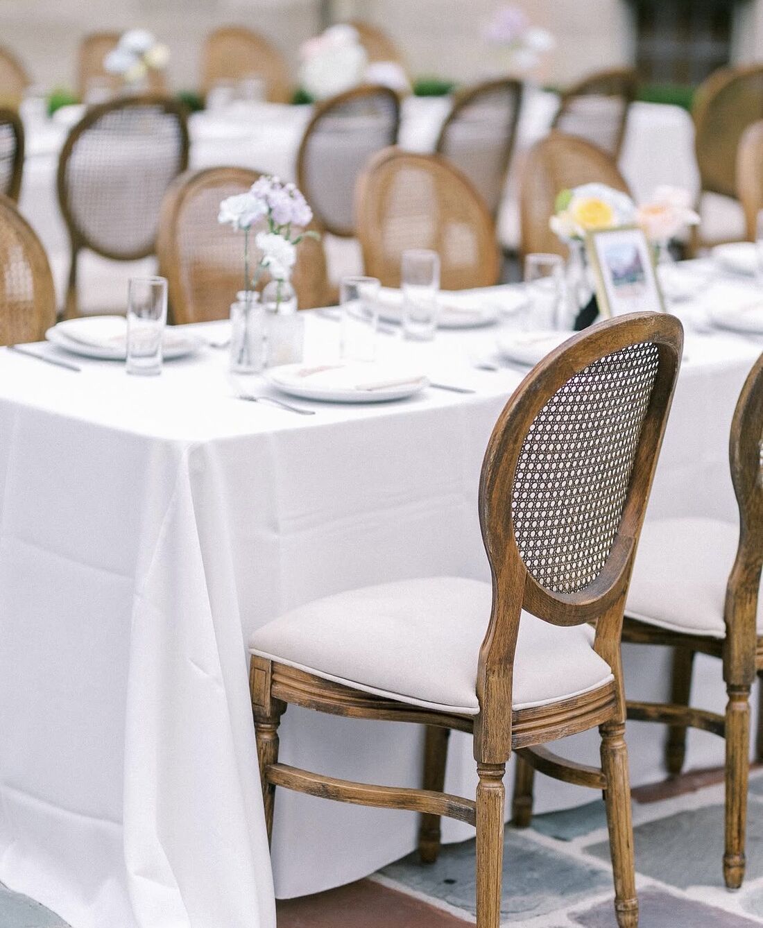 Louis chairs in carved oak with oval cane backs at a white linen table