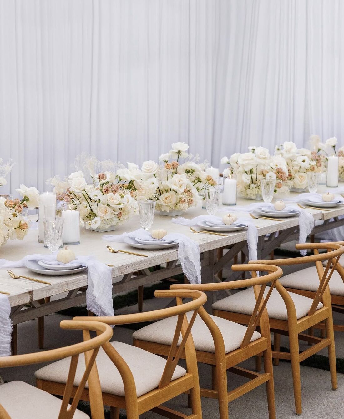 Wishbone chairs and ivory florals down a whitewashed farm table